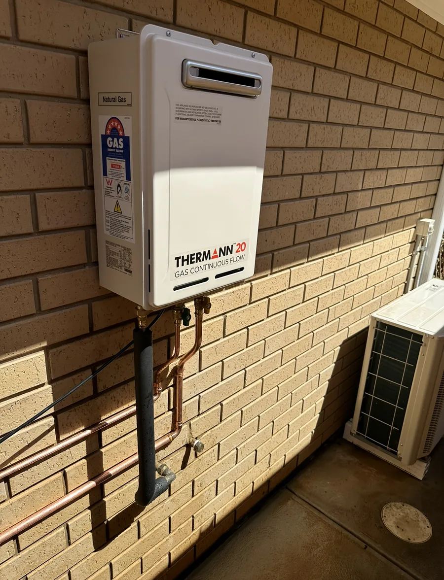 New Thermann continuous-flow gas hot water system mounted on a brick wall after replacement